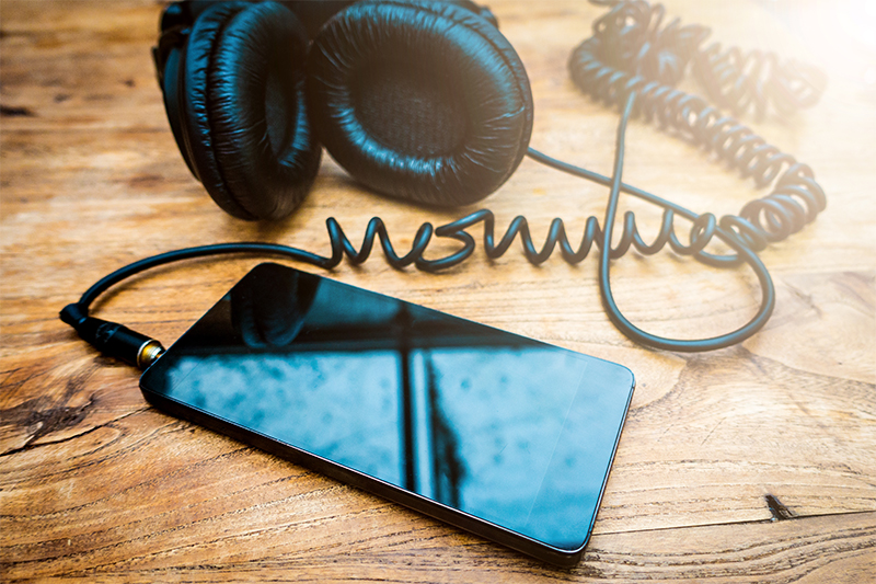 Mobile phone and headphones lay on a table ready for podcast recording