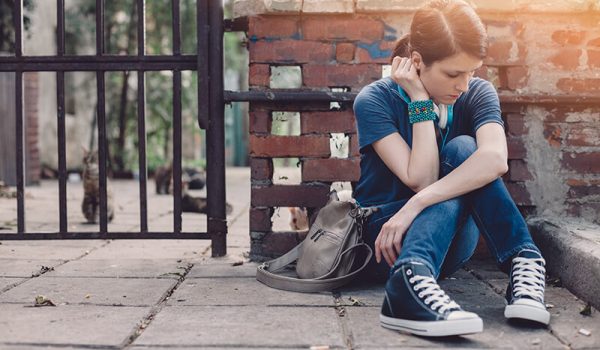 A student sits alone on the steps looking upset