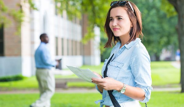 First year female College student on campus looking for class with map in hand