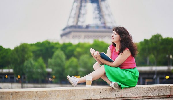 Female student reading book by the Eiffel Tower