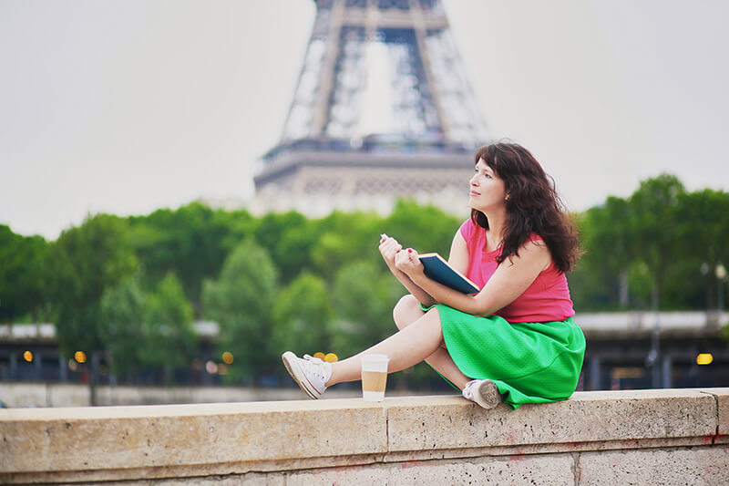 Female student reading book by the Eiffel Tower