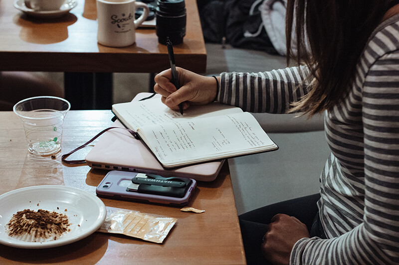 Female college student organizing her notes in a cafe