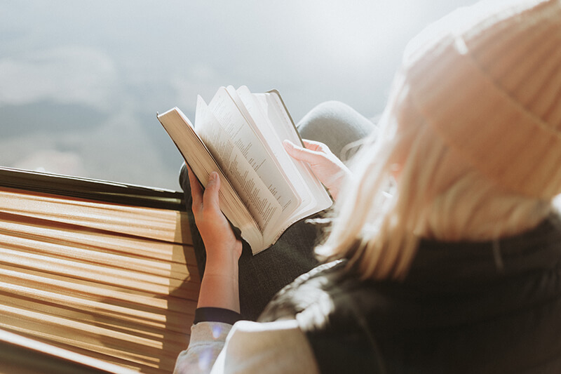 Blond university student reading a book for her book report