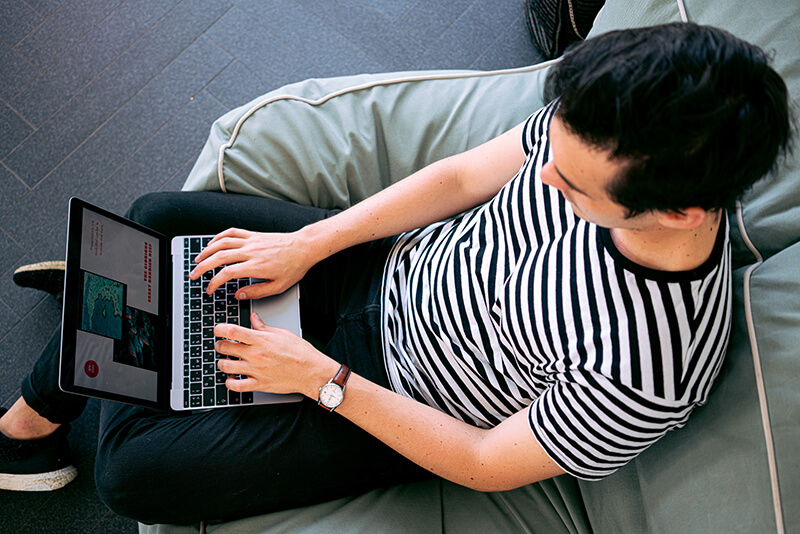 Male student in striped shirt doing an online class on his computer