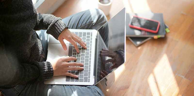 Female student sitting on the floor with online classes and study materials