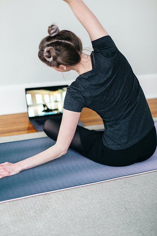 Female student doing an online course in yoga stretching