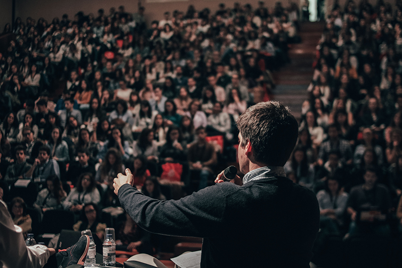 Young man giving a speech to a big audience