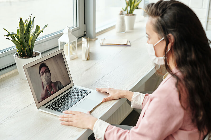 Student in self-isolation with mask on a Zoom call