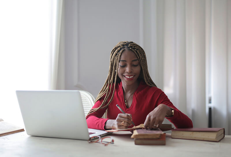 University student writing an essay at a desk with her laptop