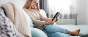 Student on couch reading an essay writing ebook