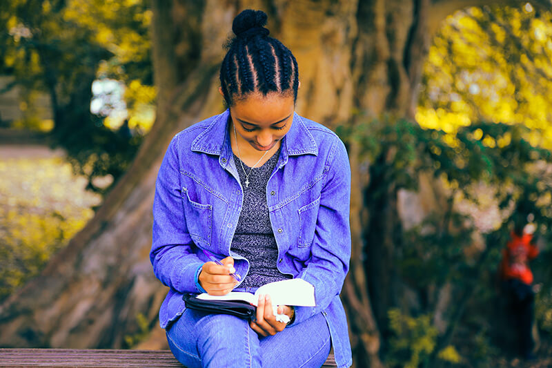University student analyzing a text among the trees