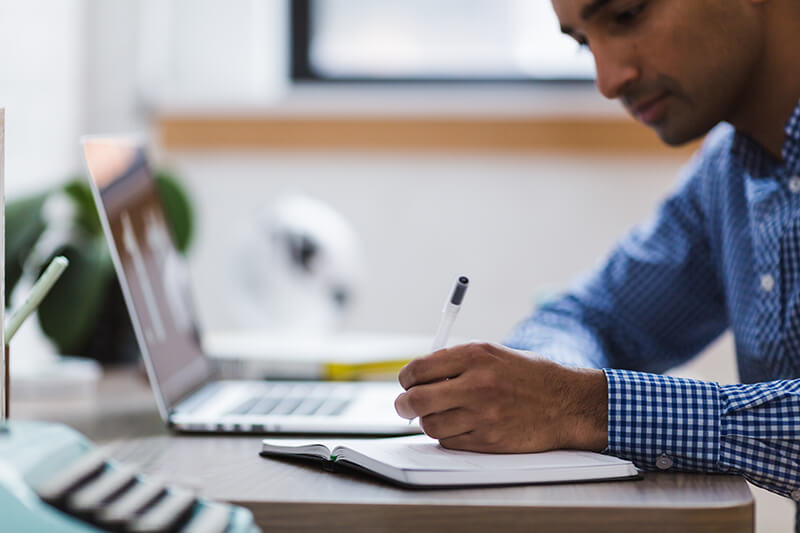 Young man writing an analytical essay using his laptop