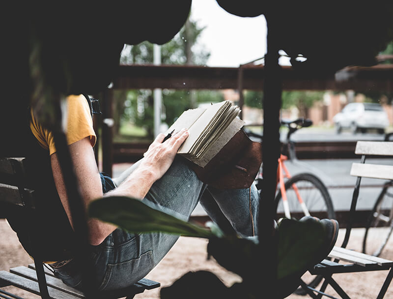 Female college student writing an essay outside on a bench