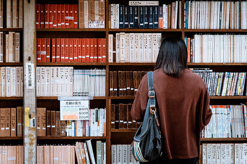 Asian student at the library looking for referencing materials