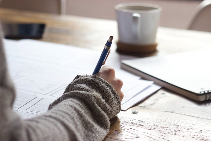 Student with pen and paper practicing different writing styles