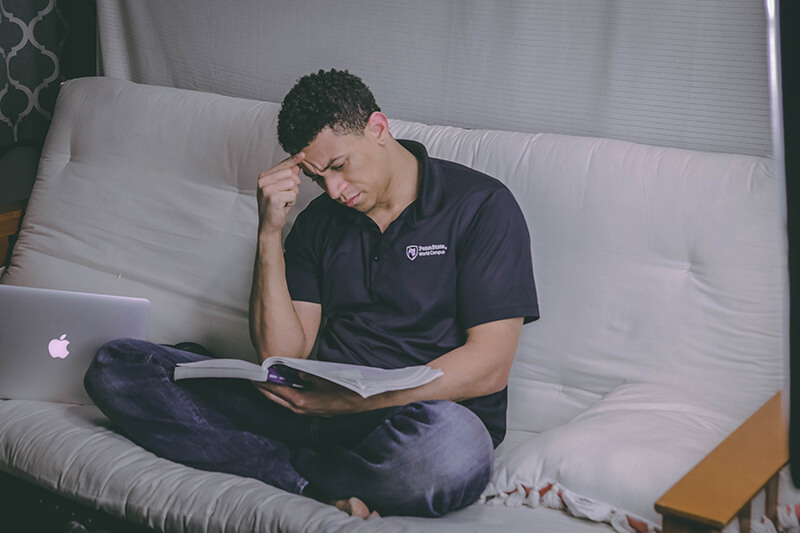 Young man sitting on the couch looking at research for essay citations