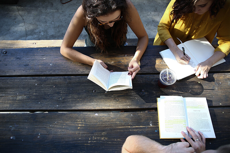 Group of students studying and writing on a table outdoors