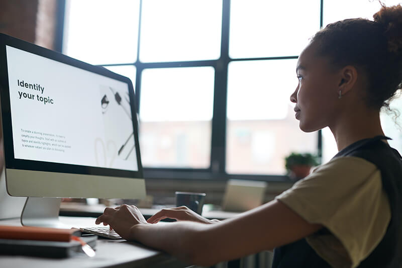 Young female student writing in proper essay format on her desktop computer