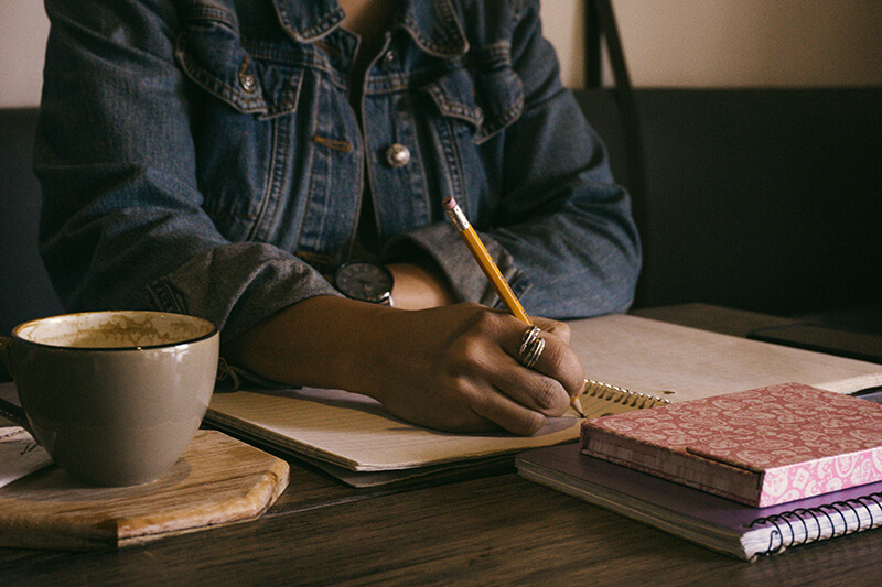 Female student writing out her main points using a pencil and paper