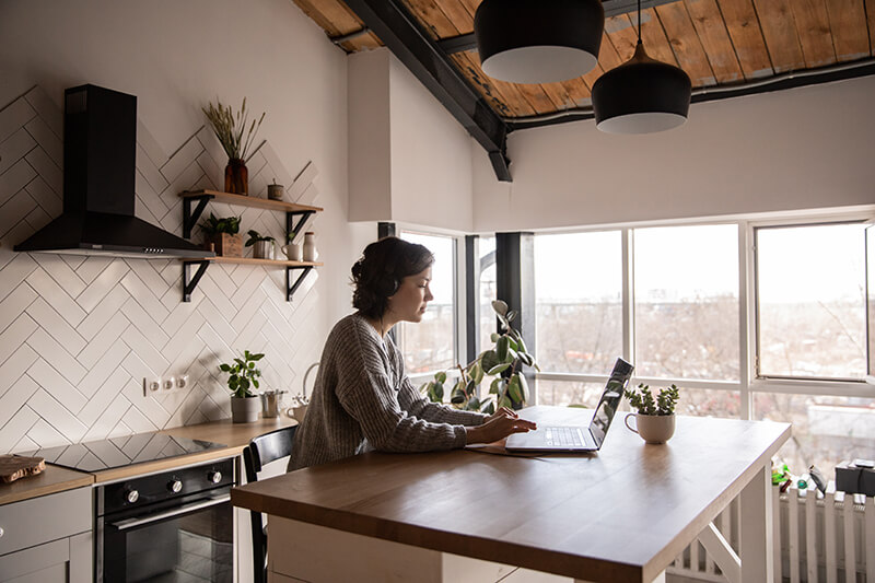 Female college student sitting in the kitchen writing argumentative essays