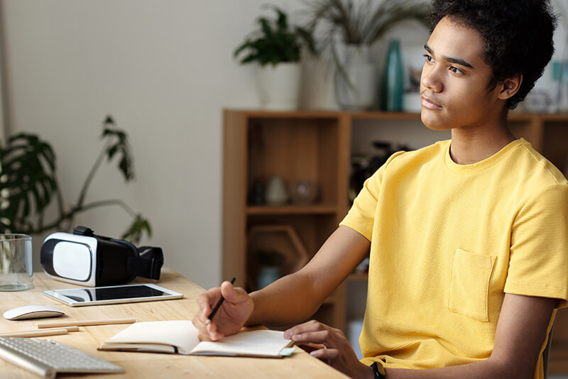 Male student in a yellow shirt looking at a precis example for studying