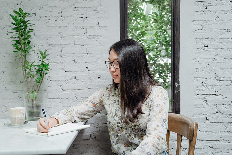 College student highlighting notes in a book at a table