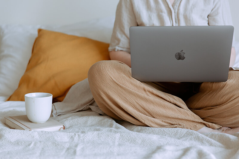 Female sitting cross legged on her bed working on a thesis