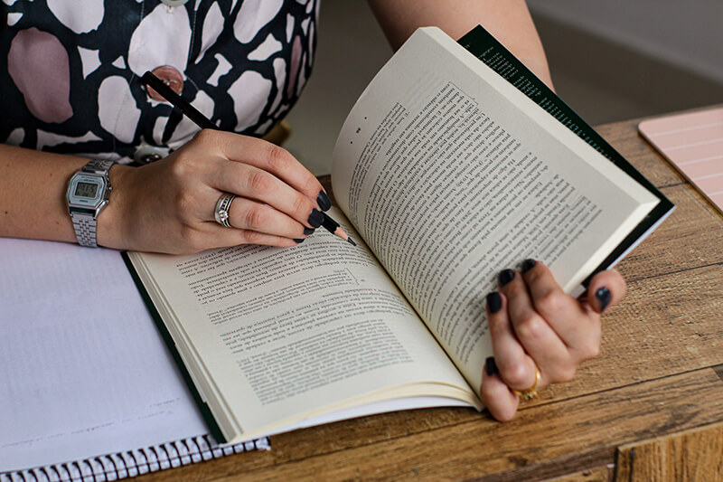 Closeup shot of a female student reading a book for her character analysis essay