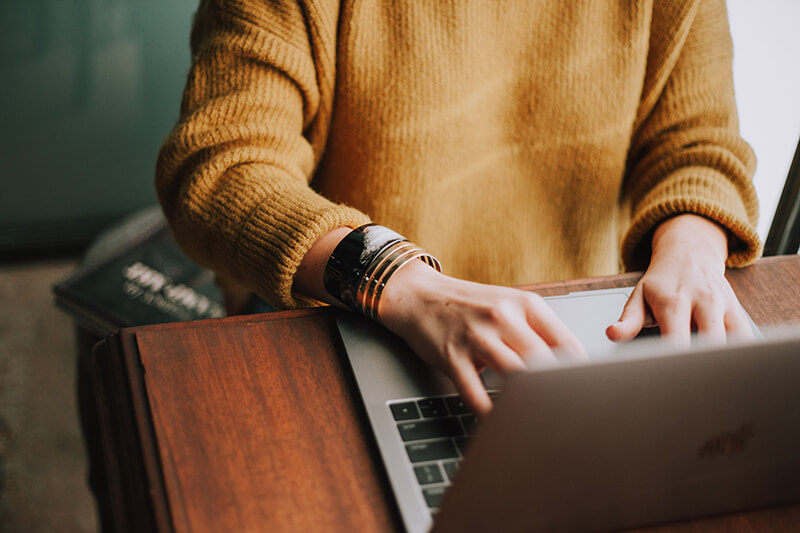 Closeup of a woman’s hands writing on a laptop keyboard