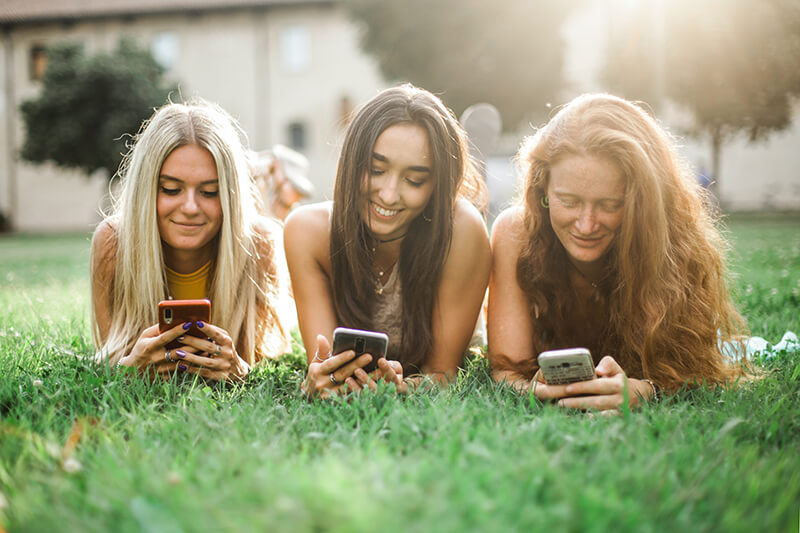 Group of friends laying in the grass browsing social media