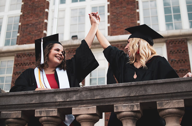 Two female graduates of an elite school celebrating together
