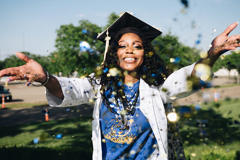 Female ivy league university graduate throwing confetti in the air