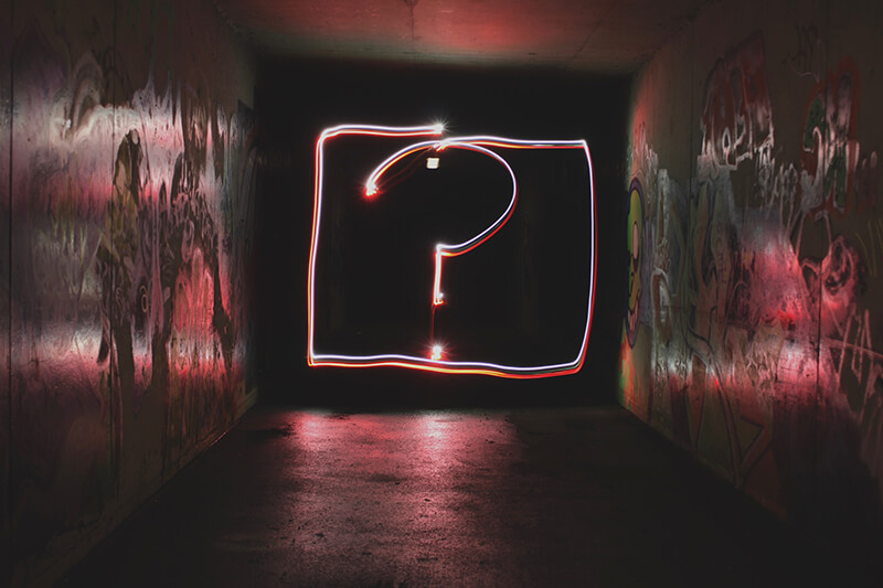 Neon sign in a hallway displaying a question mark