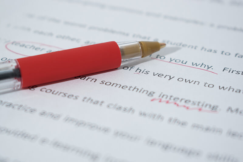 Closeup of red pen marking an essay with grammar mistakes