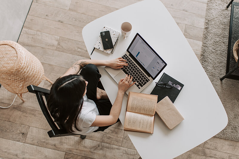 Female ESL student writing a paper in her living room on a laptop