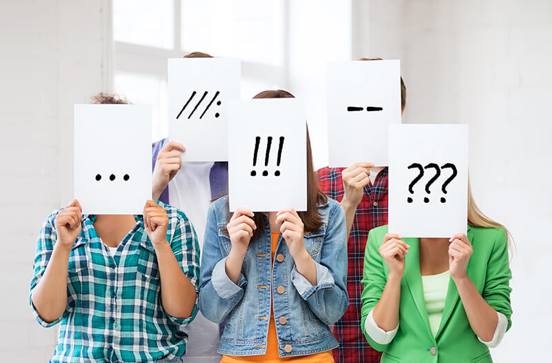 Group of students holding up signs with punctuation marks