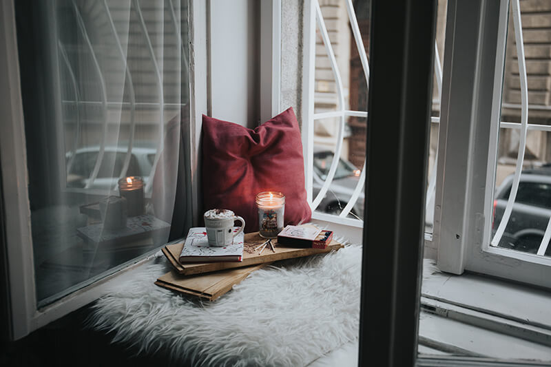 Tray with wellness candles and mood boosting supplies on a cozy corner of a bed