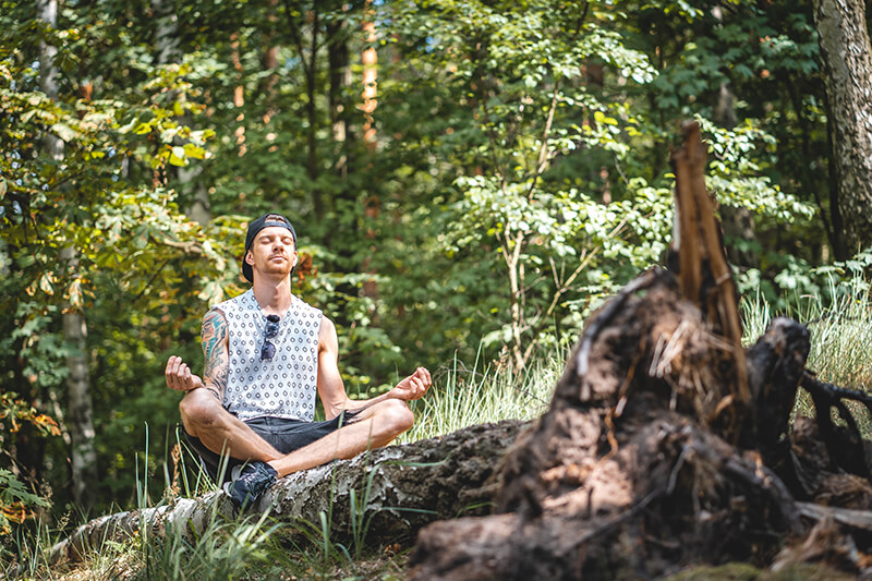 Young man sitting outside meditating for his mental health