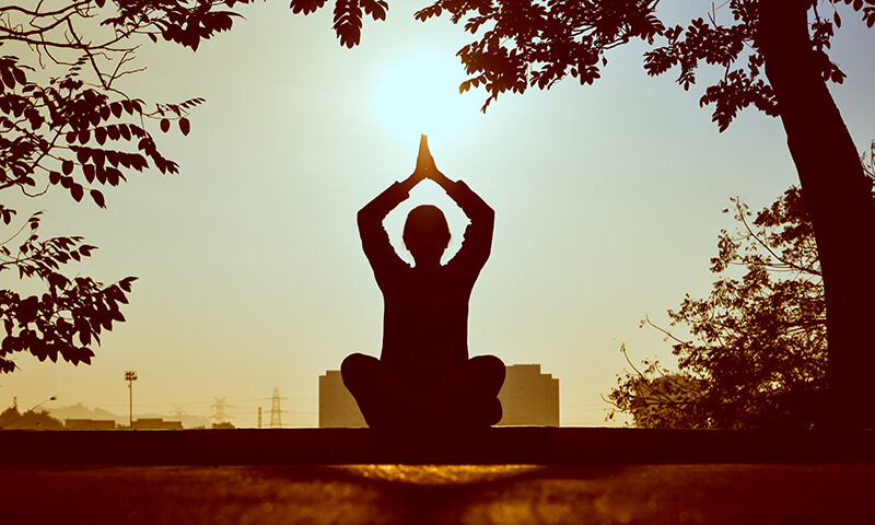 College student practicing meditation and positive daily affirmations outside