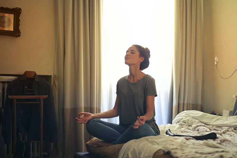 Young woman in her bed meditating and using affirmations