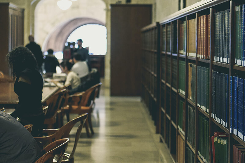 Students sitting in a library looking for books for essay citations