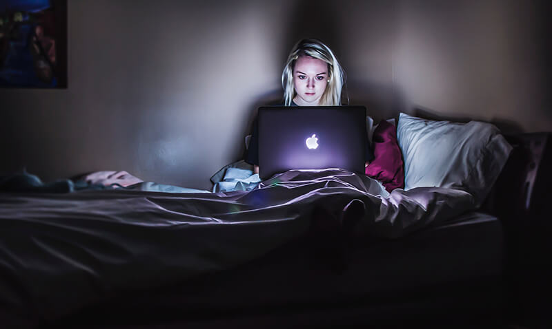 Female college student facing burnout as she studies late at night in bed