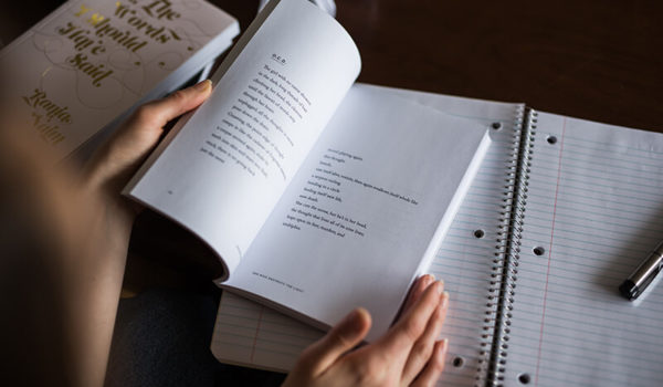 Student with a book and notepad learning how to write a literature review