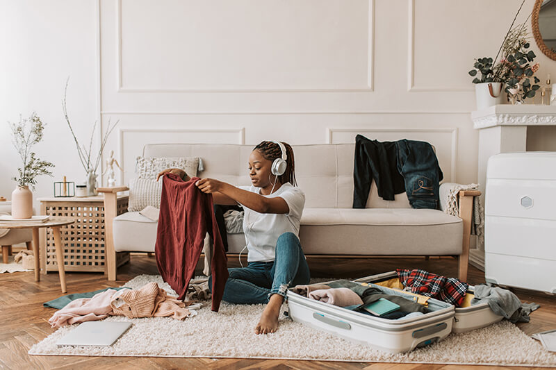 Female student packing for college while following a dorm room checklist