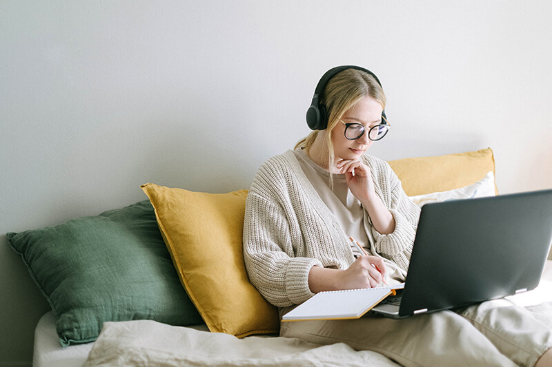 Female student using her notes to study for a test in her dorm room