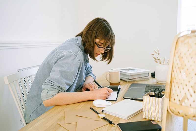 College student at a desk with a highlighter making notes in a notebook