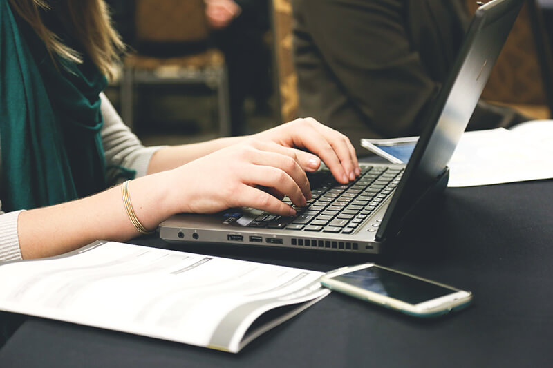 Closeup of hands typing an expository essay on a laptop