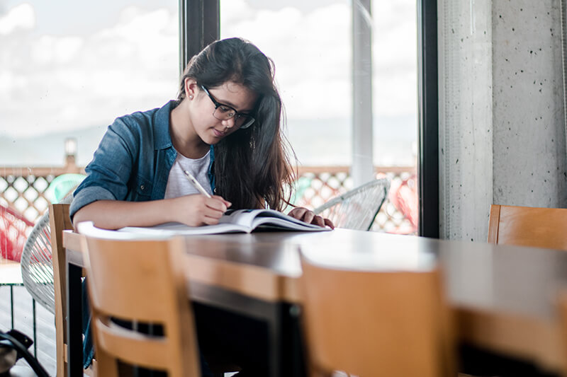 College student reviewing notes and facts sitting alone in a coffee shop