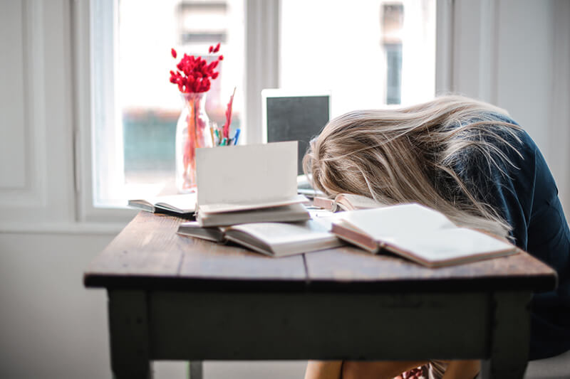 College student with head down on a pile of work tired from stress