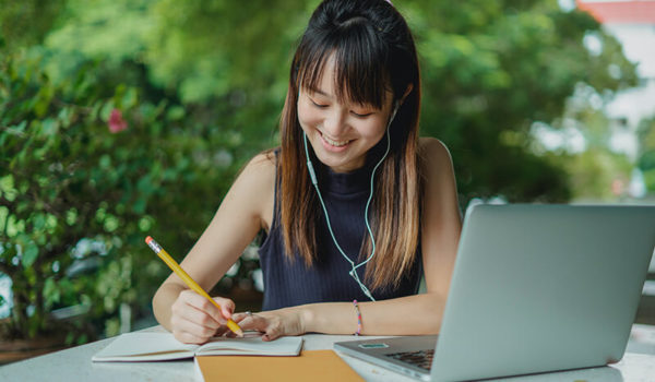 Asian college student taking notes on how to write an argumentative essay